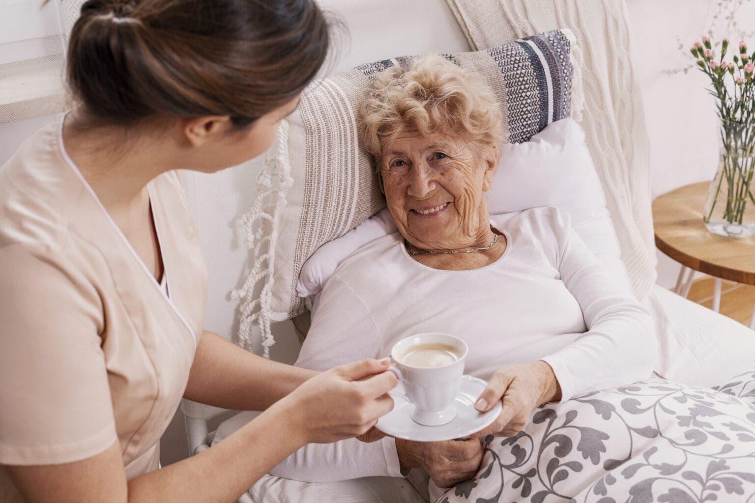 Alte Frau bekommt Kaffee ans Bett gebracht.