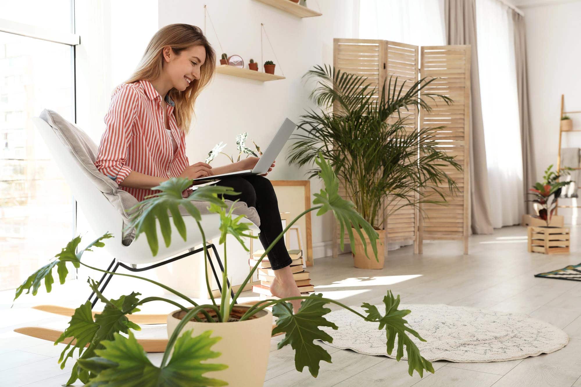 Junge Frau sitzt in modern eingerichtetem Zimmer am Laptop.