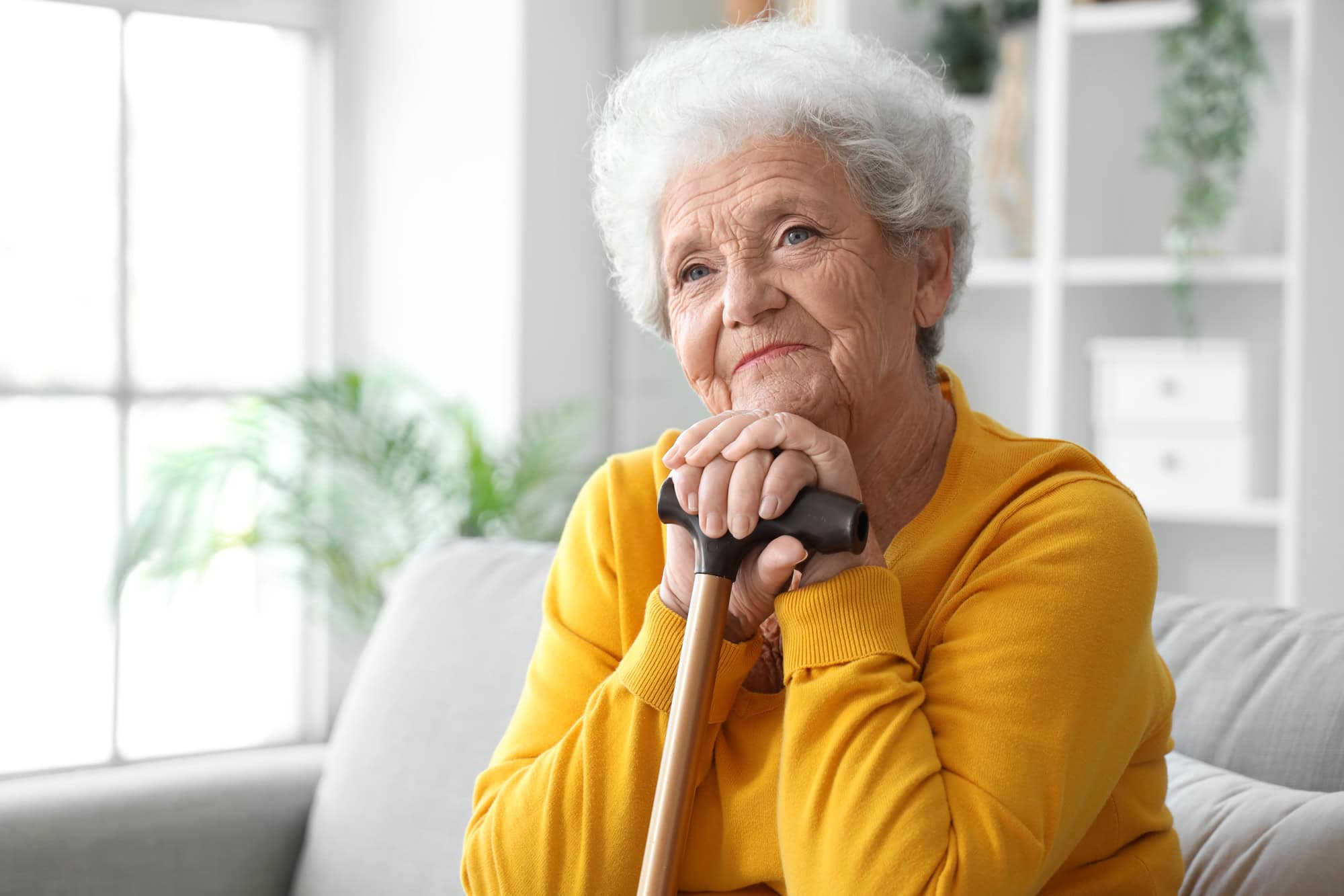 Seniorin lehnt nachdenklich an Stock